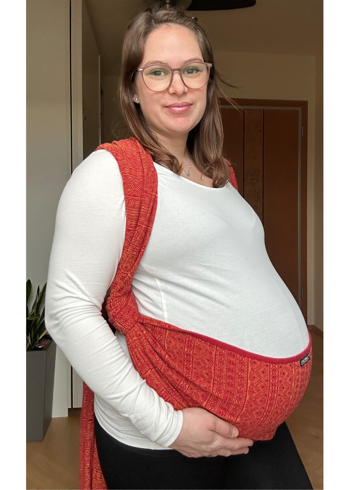 Schwangere Frau mit einem Tragetuch, das ihren Bauch sanft stützt und für Linderung von Rückenschmerzen und Beckenbodenschwäche sorgt.