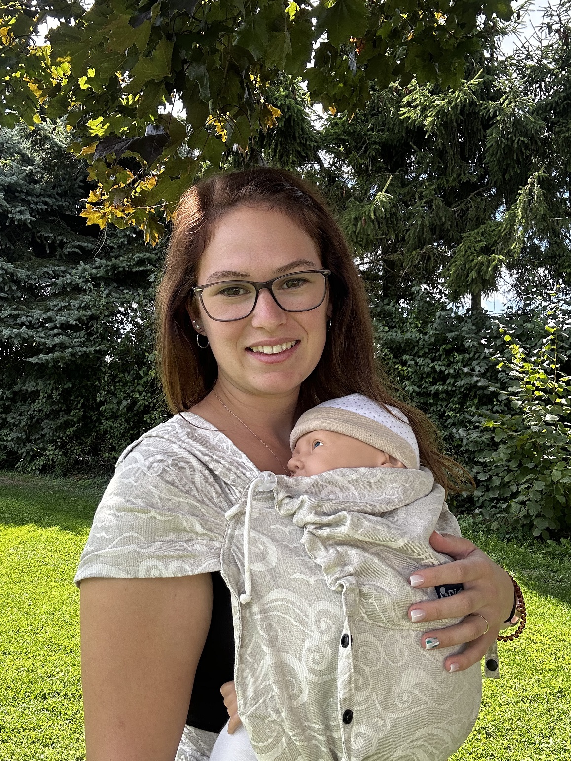Frau trägt ein Baby in einem gewebten Tragetuch mit Sternenmotiv