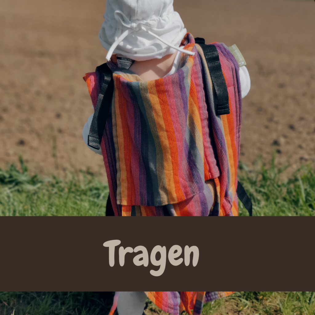 Kind in ergonomischer Trage am Rücken einer Elternperson